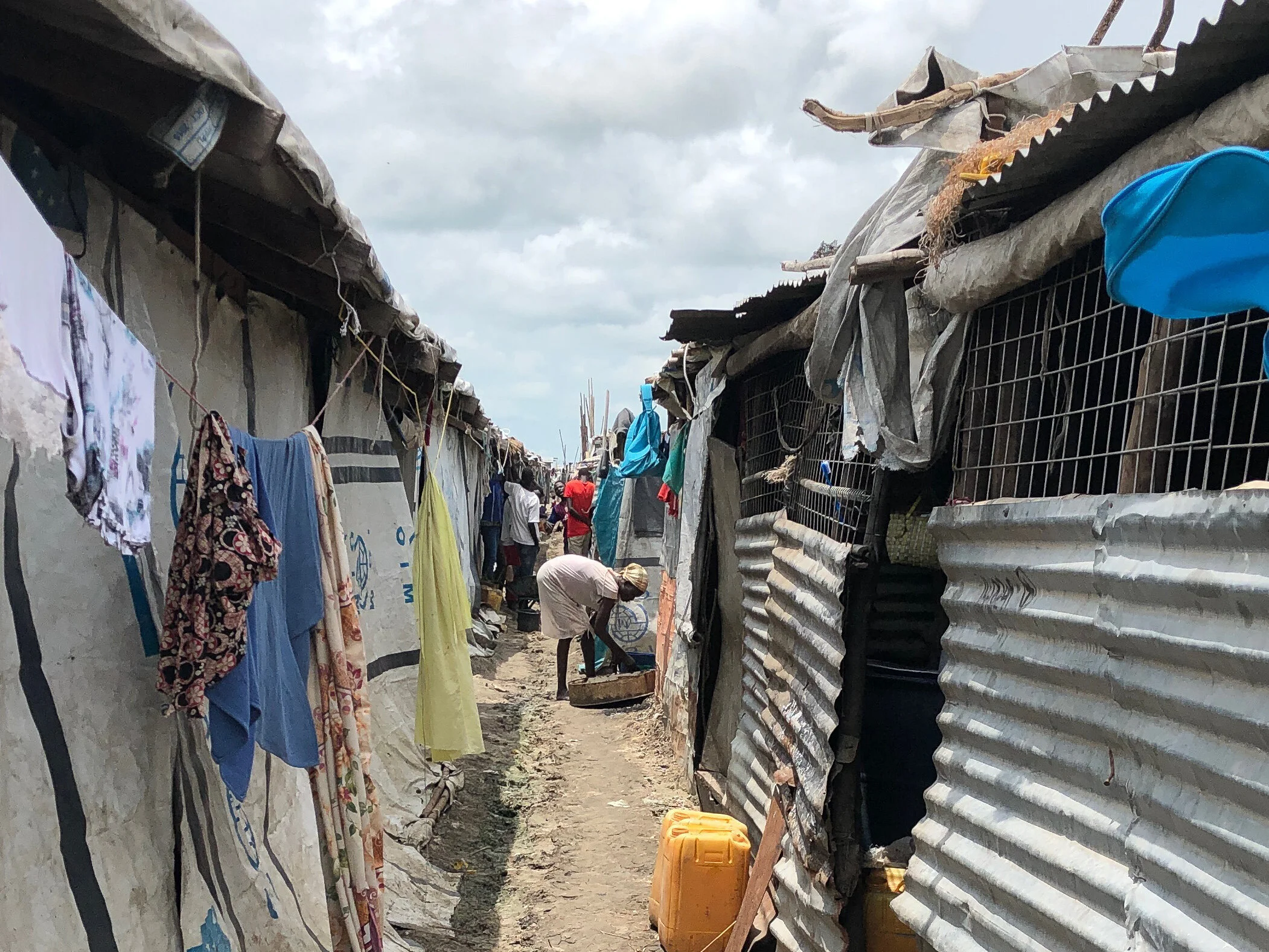 A girl washes clothes outside her house in the Malakal PoC. Photo Credit: Devon Cone/Refugees International.
