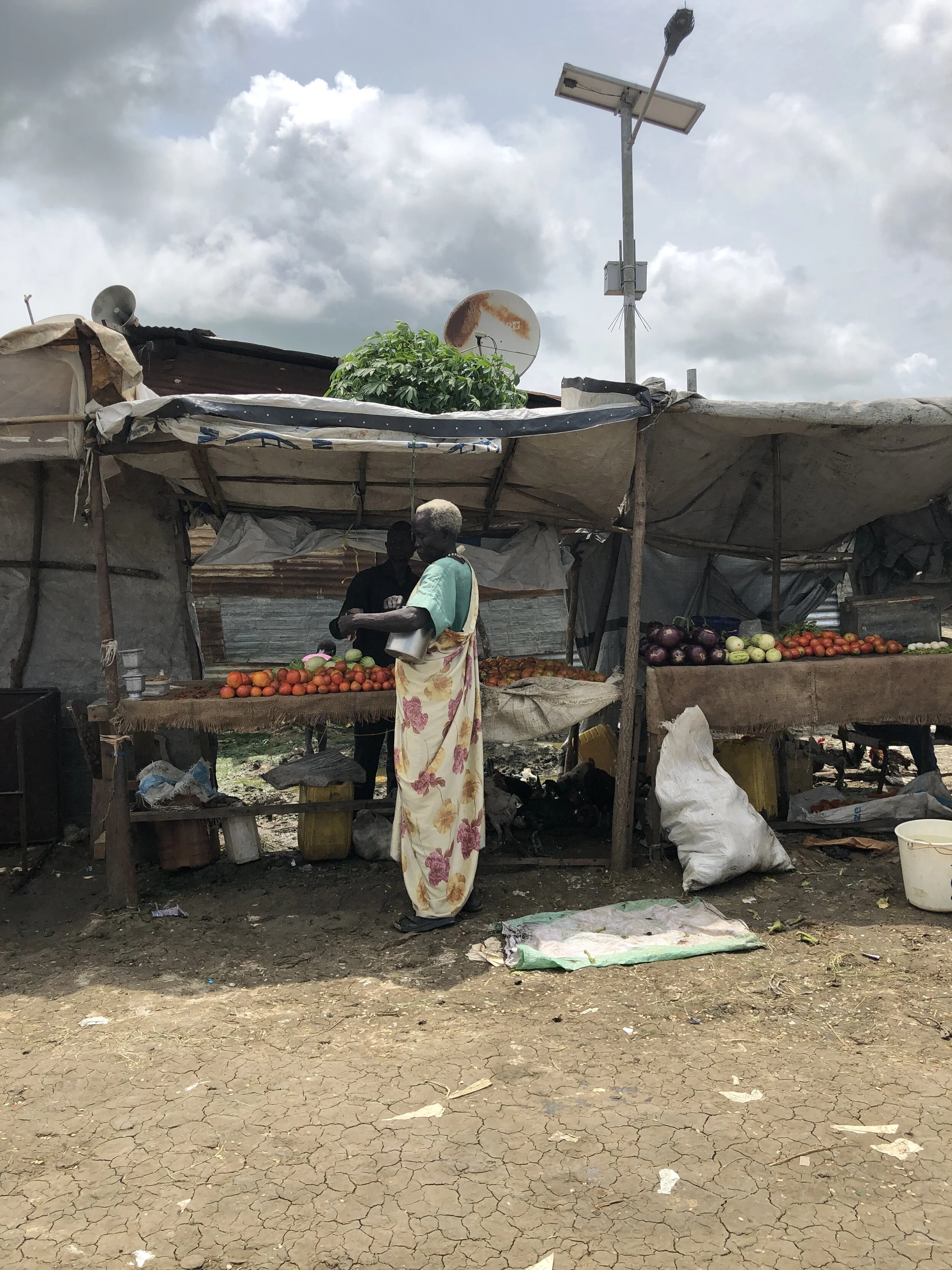 An older woman buys vegetables at a market within the Malakal PoC. Photo Credit: Devon Cone/Refugees International.