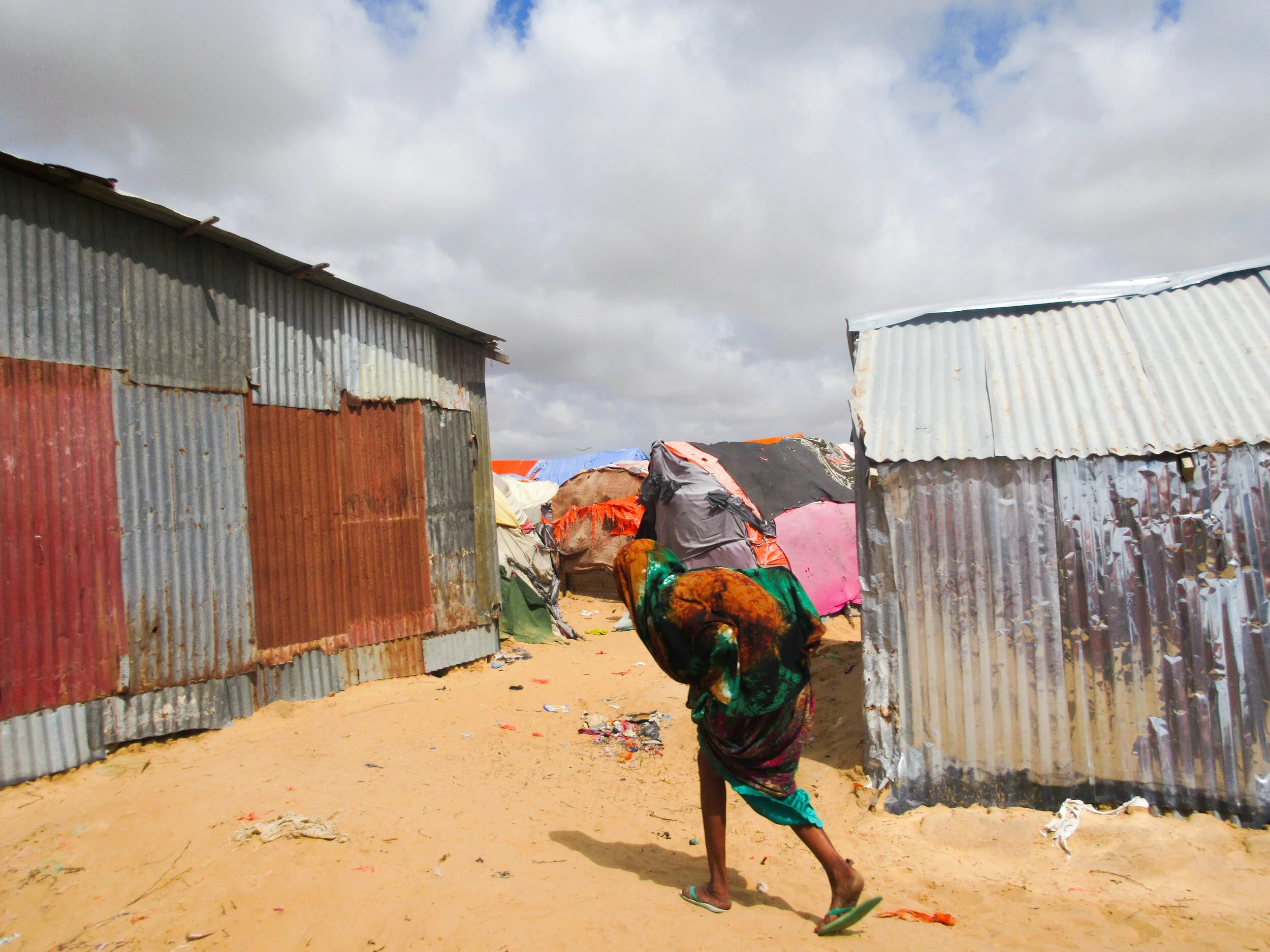 An elderly woman walks through the site for displaced people. Photo Credit: Refugees International.