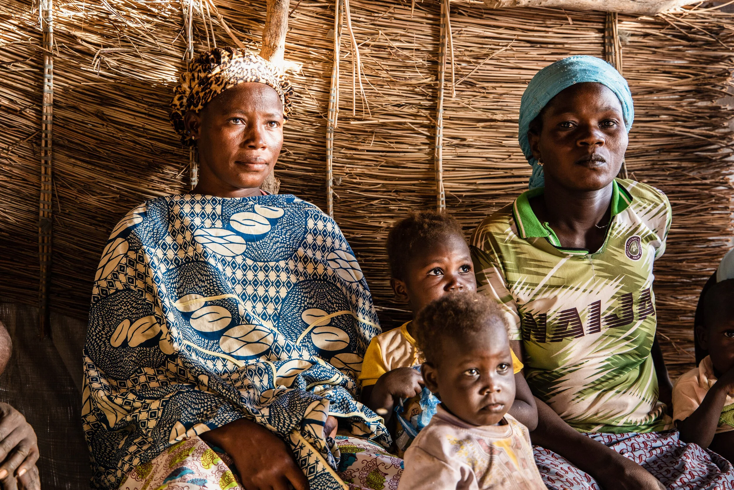 Women and children sit under a hut in a district that welcomes internally displaced people from northern Burkina Faso. Photo Credit: Olympia de Maismont/AFP/Getty Images.