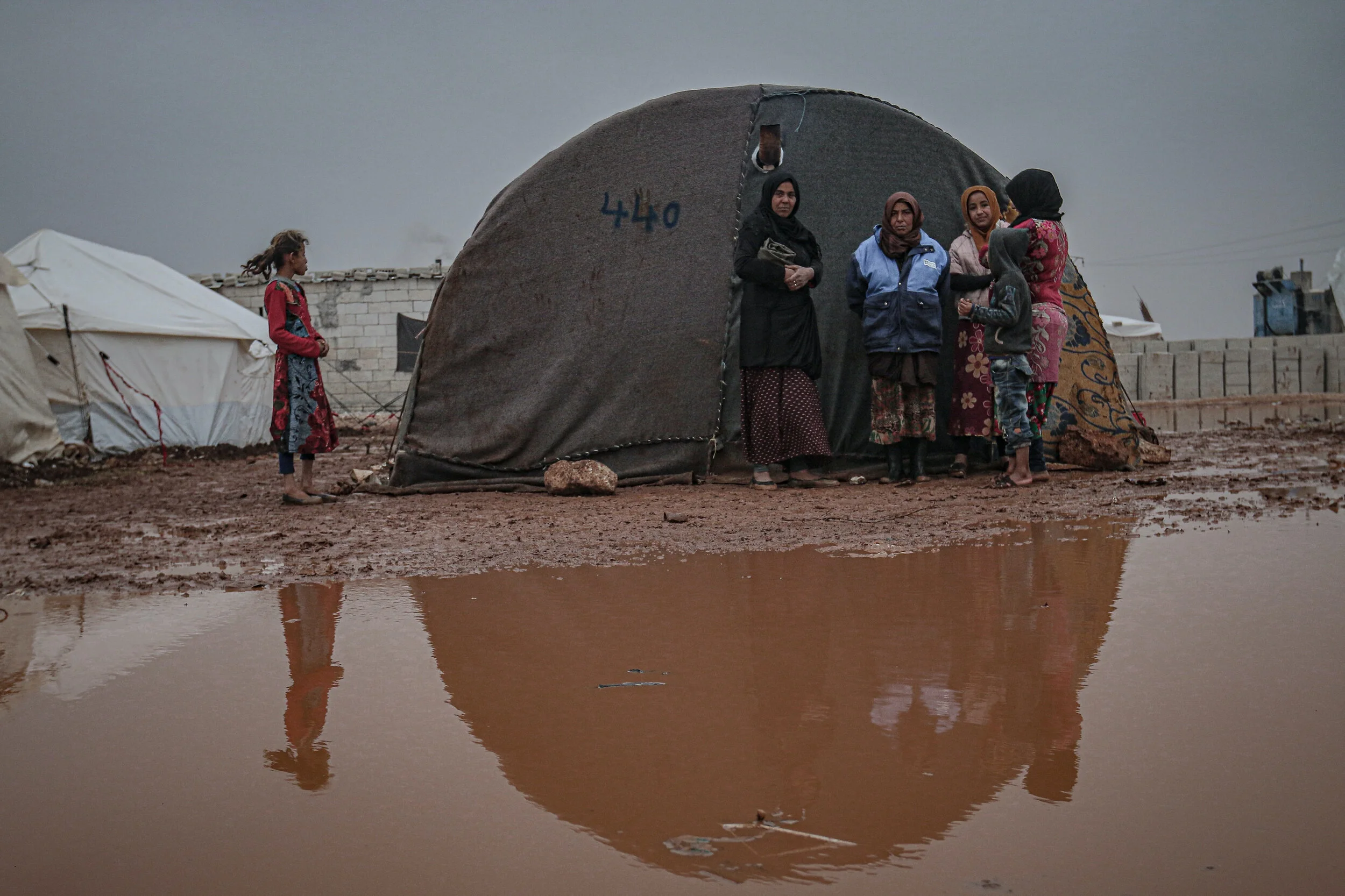 Syrians are seen on the mud covered road between tents at a refugee camp after heavy rain in Idlib, Syria. Syrian refugees, who have been living in the camp, face flooding, mud, and puddles due to lack of infrastructure and sewerage network. Photo by Muhammed Said/Anadolu Agency/Getty Images.