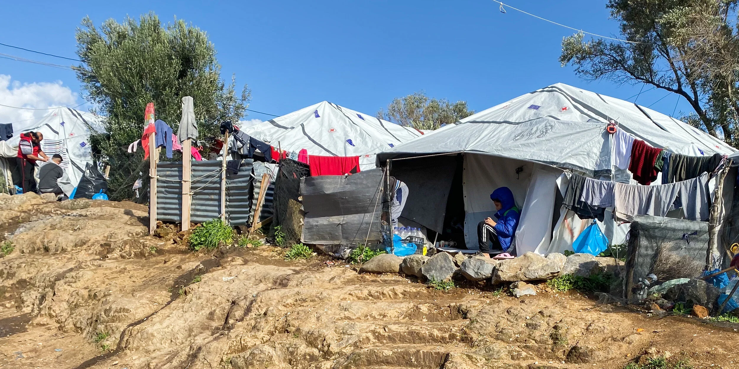 Tents and a makeshift latrine in the “Olive Grove” area outside the official Moria Reception and Identification Center on Lesvos. Photo by: Devon Cone.