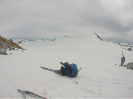 Alf Pinchak (age 79) on the right carrying his skies to the Lemon Creek Glacier while a student struggles to get up.