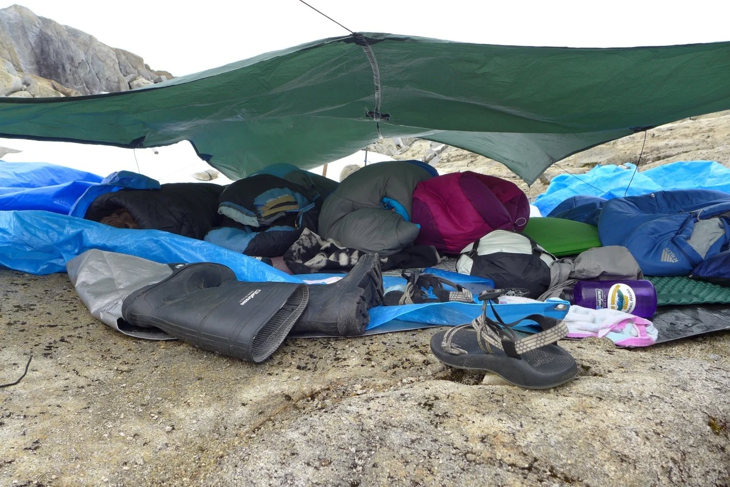 Tarp tent trial 1 : Tarp fitting 6 people. Not a very successful structure. Eventually it rained that night and there was a wind storm. The open floor plan caused heads and feet to get WET, however the wind later that morning dried everything… Photo credit : Jeffy Gunderson
