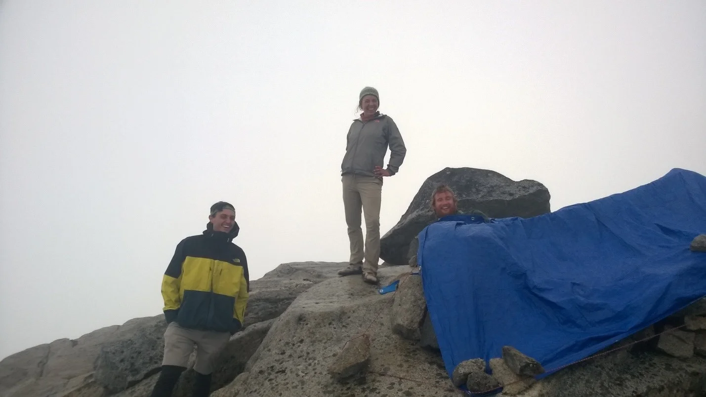 Tarp tent trial 4 : The rock fort at camp 10 took many nights and attempts to perfect. By connecting some cord to rocks with a bowline knot and creating tension, a tarp that repelled precipitation was fashioned. People from left to right : James O’Neil, Olivia Eads, and Tadhg Moore. Photo credit : Jeffy Gunderson.