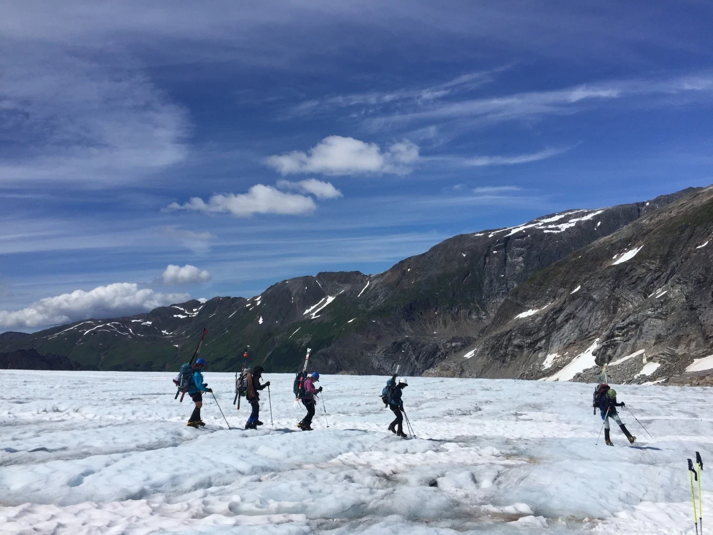 The trail party ahead of my own using crampons to navigate the ablation zone on the Lemon Creek Glacier during our mini traverse, with beautiful and dangerous blue sky above. Photo by Auri Clark.