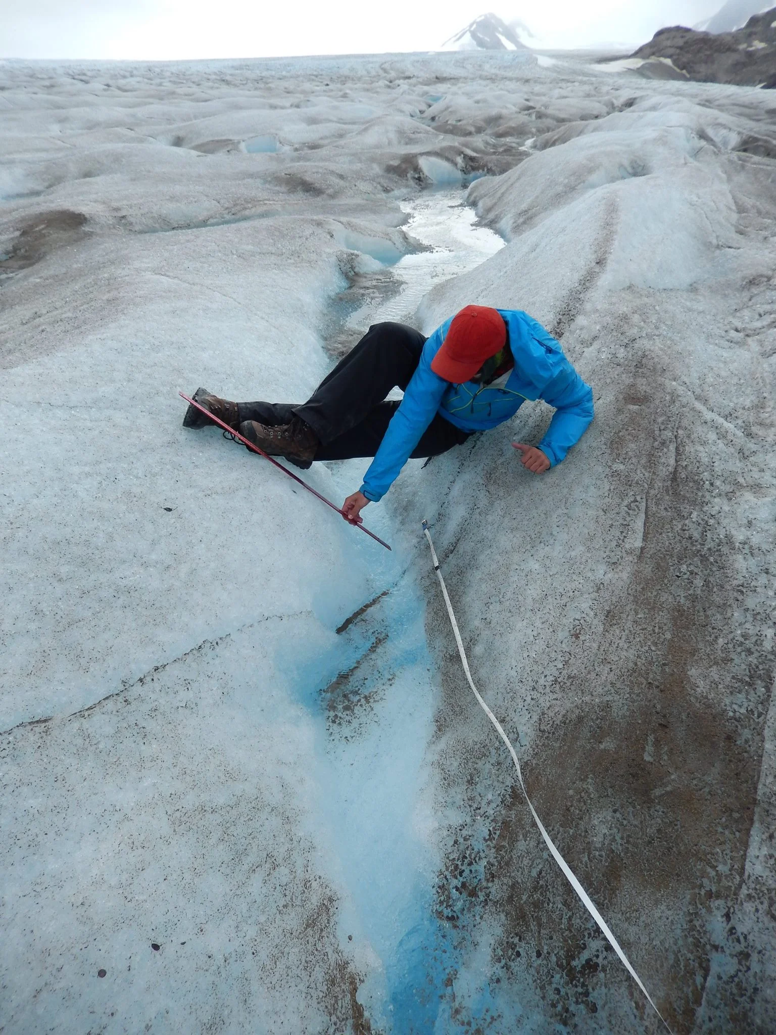 Chris Miele measures the dimensions of a supraglacial stream on the Llewellyn Glacier. Photo credit: Annie Zaccarin