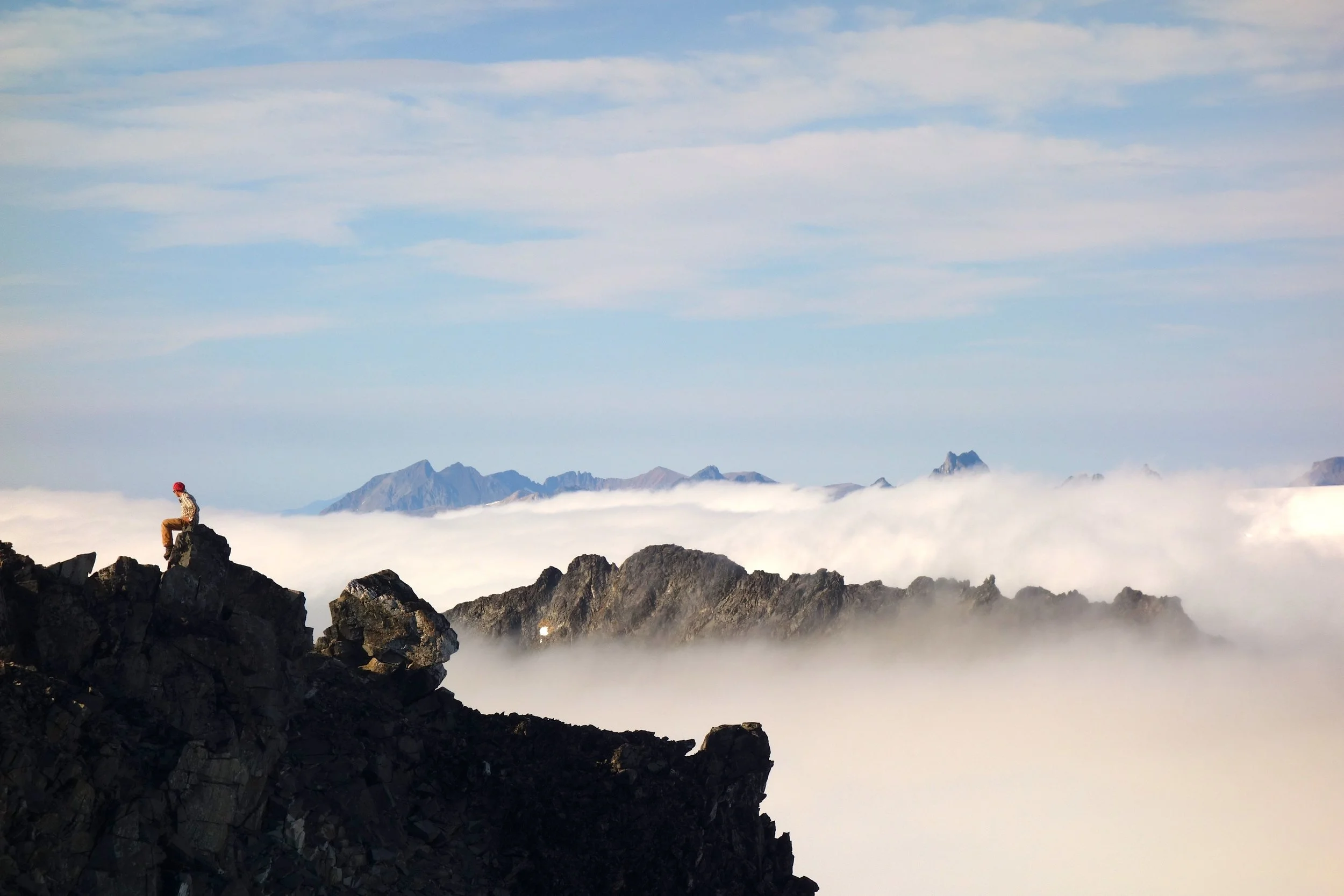 Newt Krumdieck overlooking the cloud-covered icefield from the summit of Mount Moore. Photo by Kenzie McAdams. 