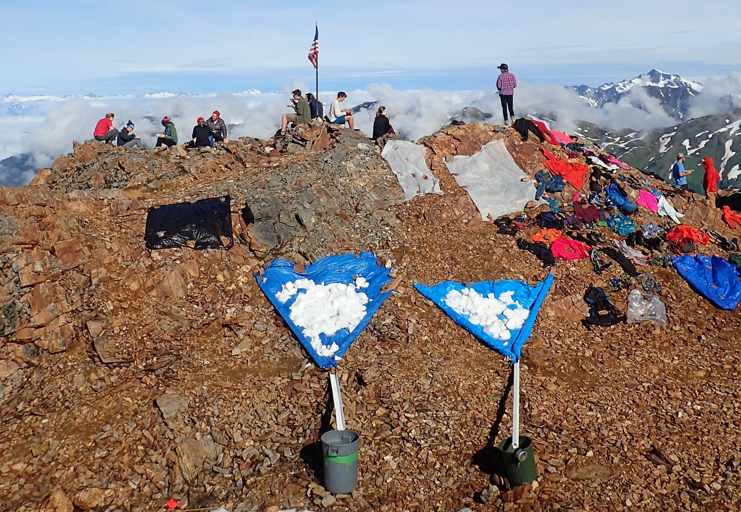 The water supply at Camp 17 is shown above, displaying the tarps onto which we shovel snow from the patch just off the bottom of the photo. A piece of white gutter connects the tarp to the trash barrel, into which the melted water drains. A sauce pan can be seen on the side of the barrel on the right, used to scoop water into buckets for transport. Photo credit: Ann Hill.