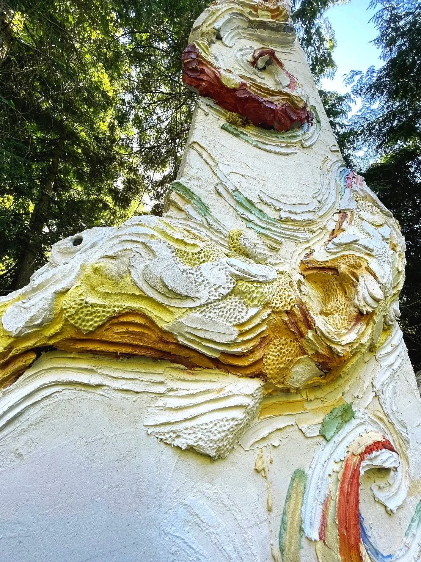 Large scale monumental and colored concrete sculpture depicting an octopus wrapped around an architectural column in an art collection sculpture private park