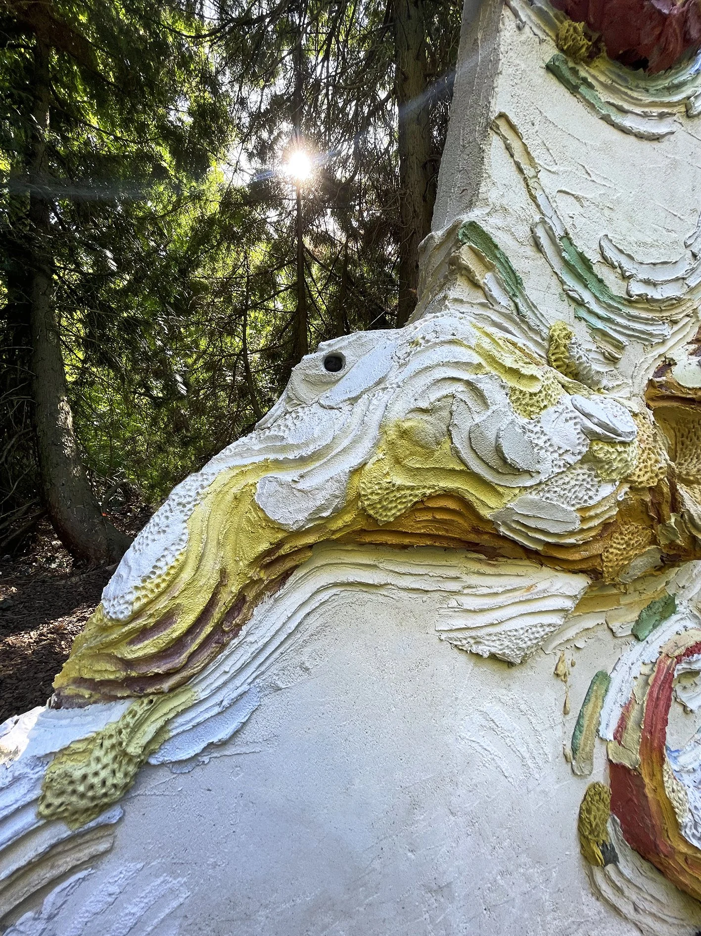 Large scale monumental scultpure made of concrete and colored mortar with extreme organic details depicting a monumental octopus wrapped arouind an architectural colummn  in a private sculpture park owned by a contemporary art collector and a museum