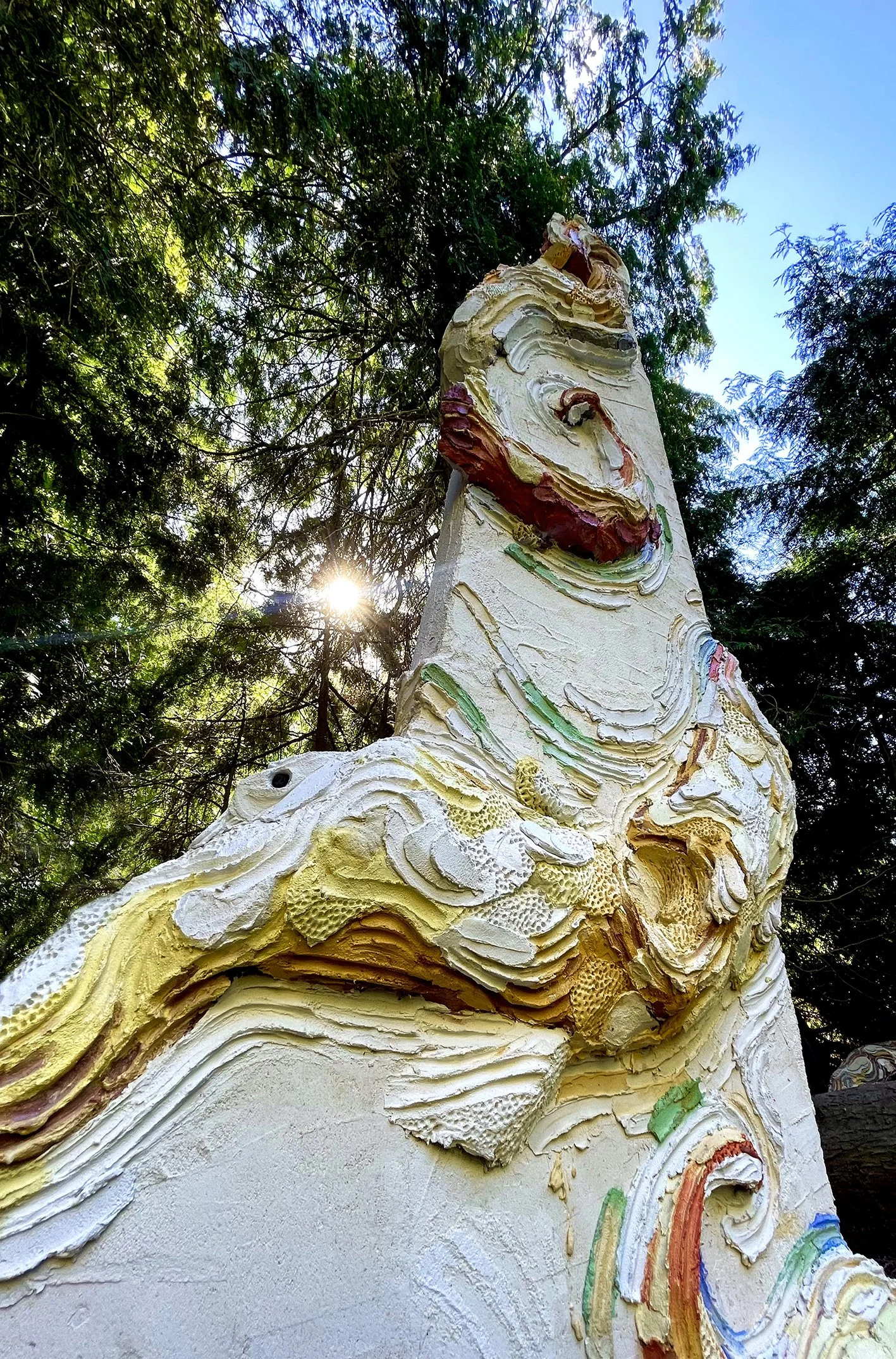 Large scale monumental scultpure made of concrete and colored mortar with extreme organic details depicting a monumental octopus wrapped arouind an architectural colummn  in a private sculpture park owned by a contemporary art collector and a museum