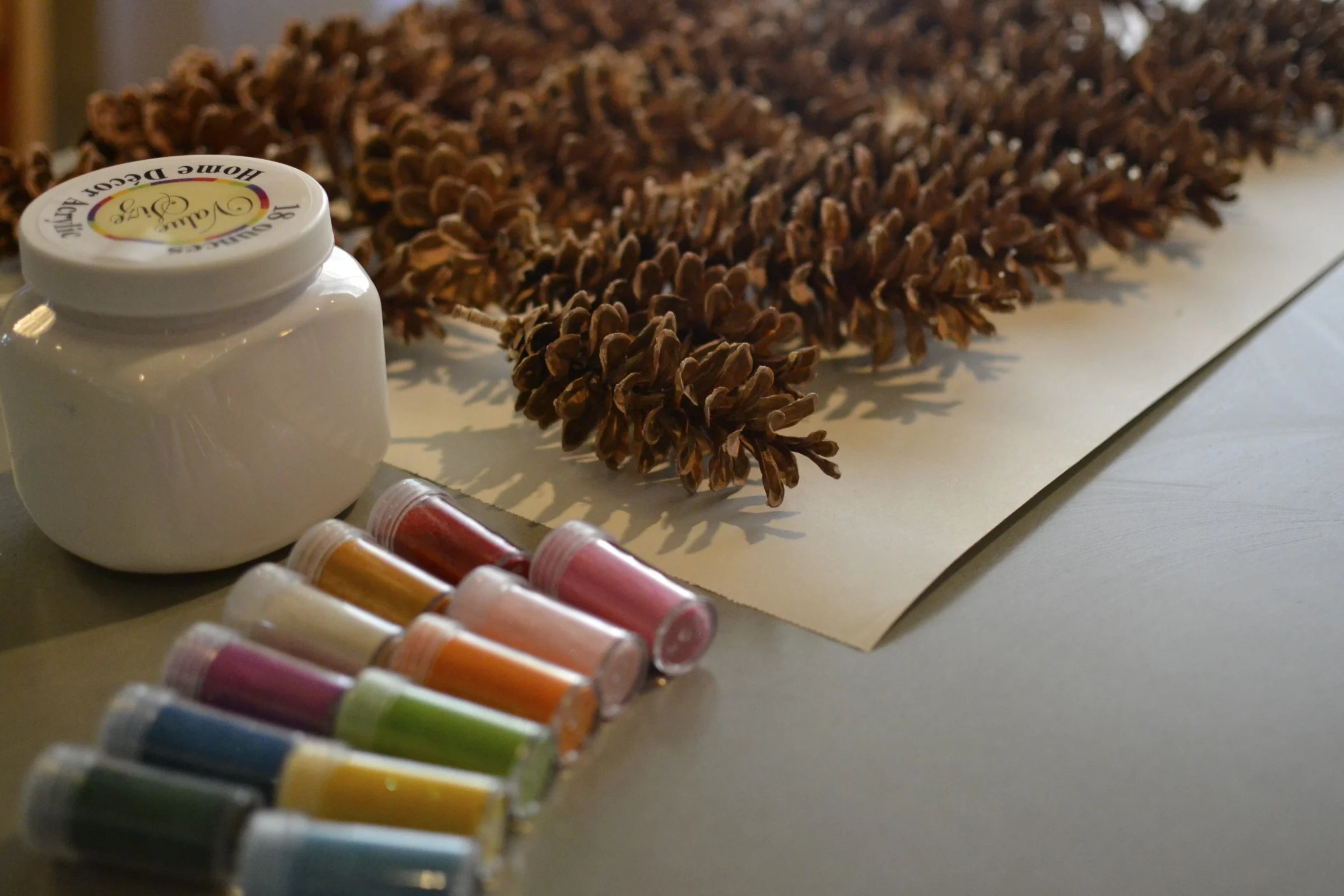 first things first...let's dip and glitter some pinecones! lay out craft paper over the entire surface you will be working on. if you didn't purchase a tub of paint, as i did, you can pour your paint into a larger container for dipping. i found my pinecones while out on a walk and they were still pretty covered in sap. if this is the case, you might want to wear latex gloves while working with them. 