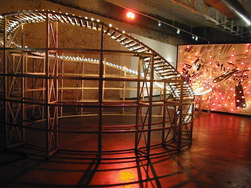 Malfunction Junction , 2004, wood structure with chasing lights, wall drawing with spiral of erratically blinking lights and soundtrack (electrical drones and clicks, re-verbed music box and rock/punk/car songs) , wood structure 8.5 x 13.5 x 23', wall drawing 10 x 10’
