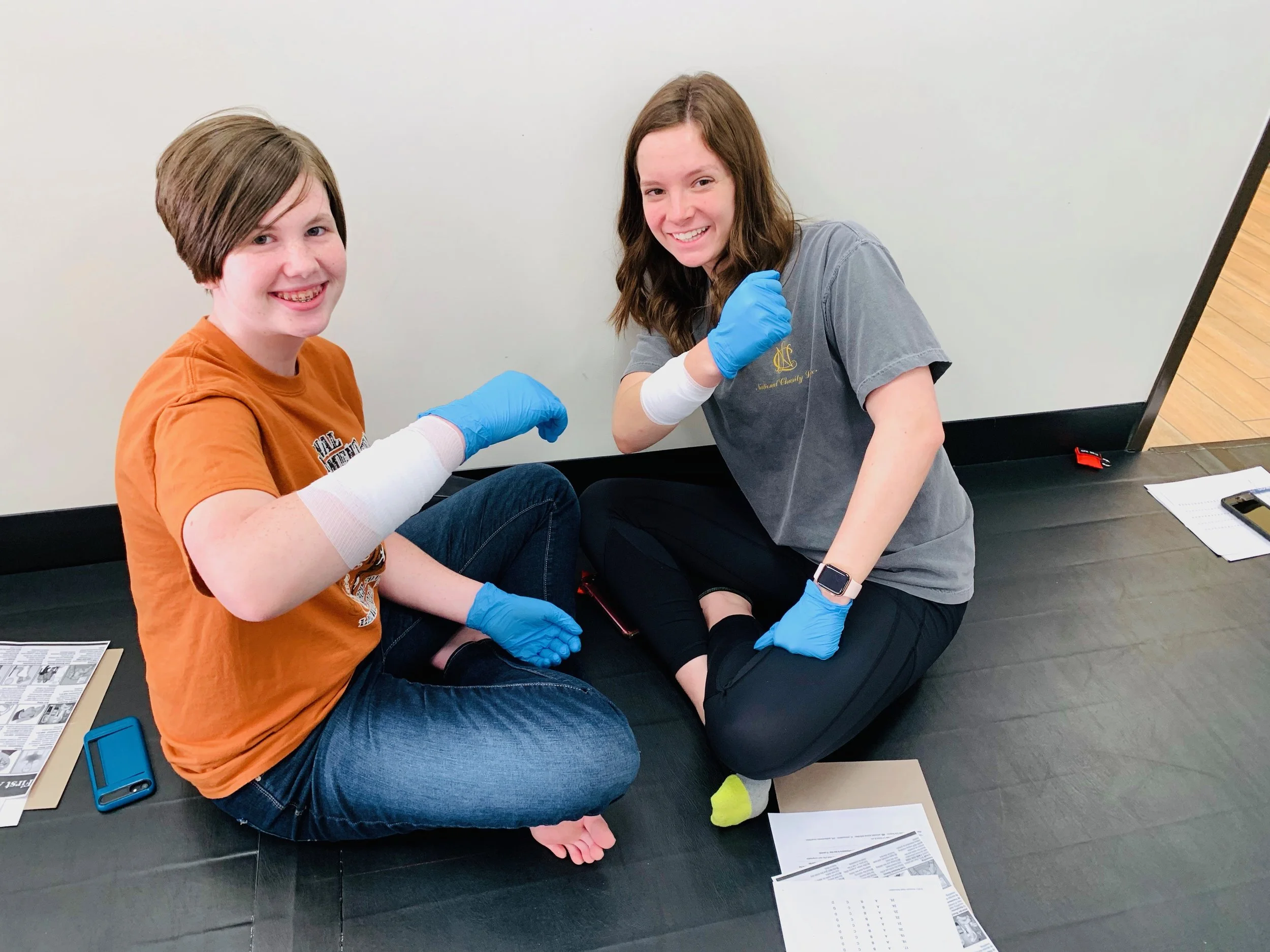 Miss Harroff and Miss Moore helping each other learn First Aid.