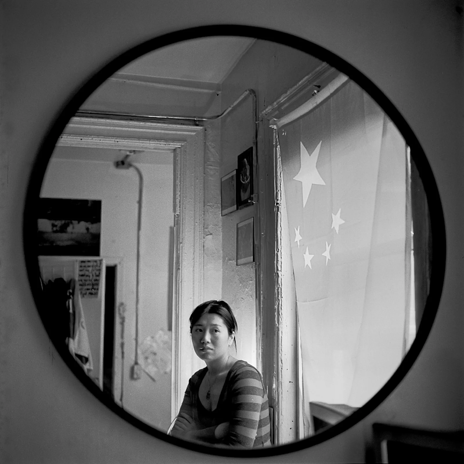 Day 2 This is a portrait of Davina, an inspiring lady who is simultaneously a social worker, activist, and poet working in Chinatown, NY. I had the pleasure of meeting her in 2009, in my early days of documenting the neighborhood when I was still shooting B&W film. This image also represents a turning point in my work. Always, when I see this image, I picture it in bold red and yellow hues, colors that flooded the room and her petite frame as the late afternoon light shone through the towering Chinese flag hung proudly across her bedroom window. I wished at that moment I had carried color film with me instead... the intense, symbolic red glow emanating from the flag, changed the mood and tone of the situation completely. The following day, I went out and bought as much color film as I could afford at the time. Till now, I've stuck to working with color when photographing in Chinatown.