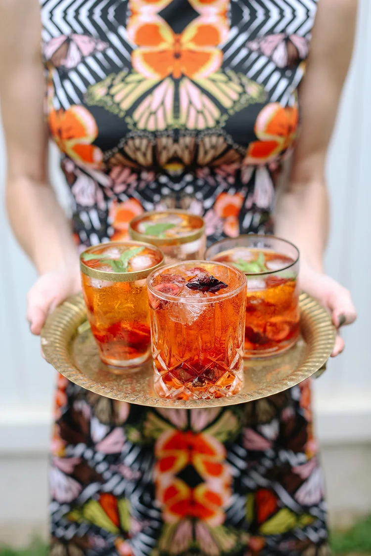 Aperol Spritz served in Double Old Fashioned glasses and garnished with chocolate cosmos and mint. See recipe below. 