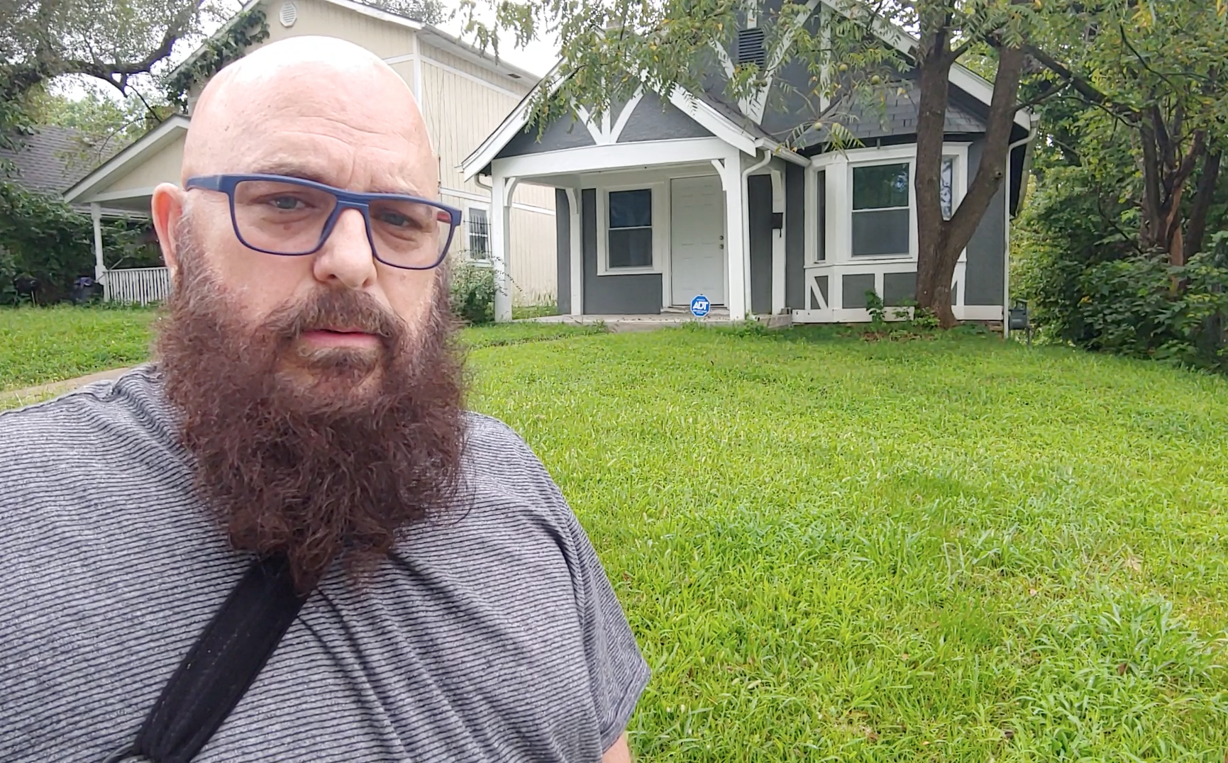Danny Tipton stands in front of a home that GT Home Solutions rehabbed on Broadmoor, which now has an owner-occupant. The house was restored from the condition shown above.