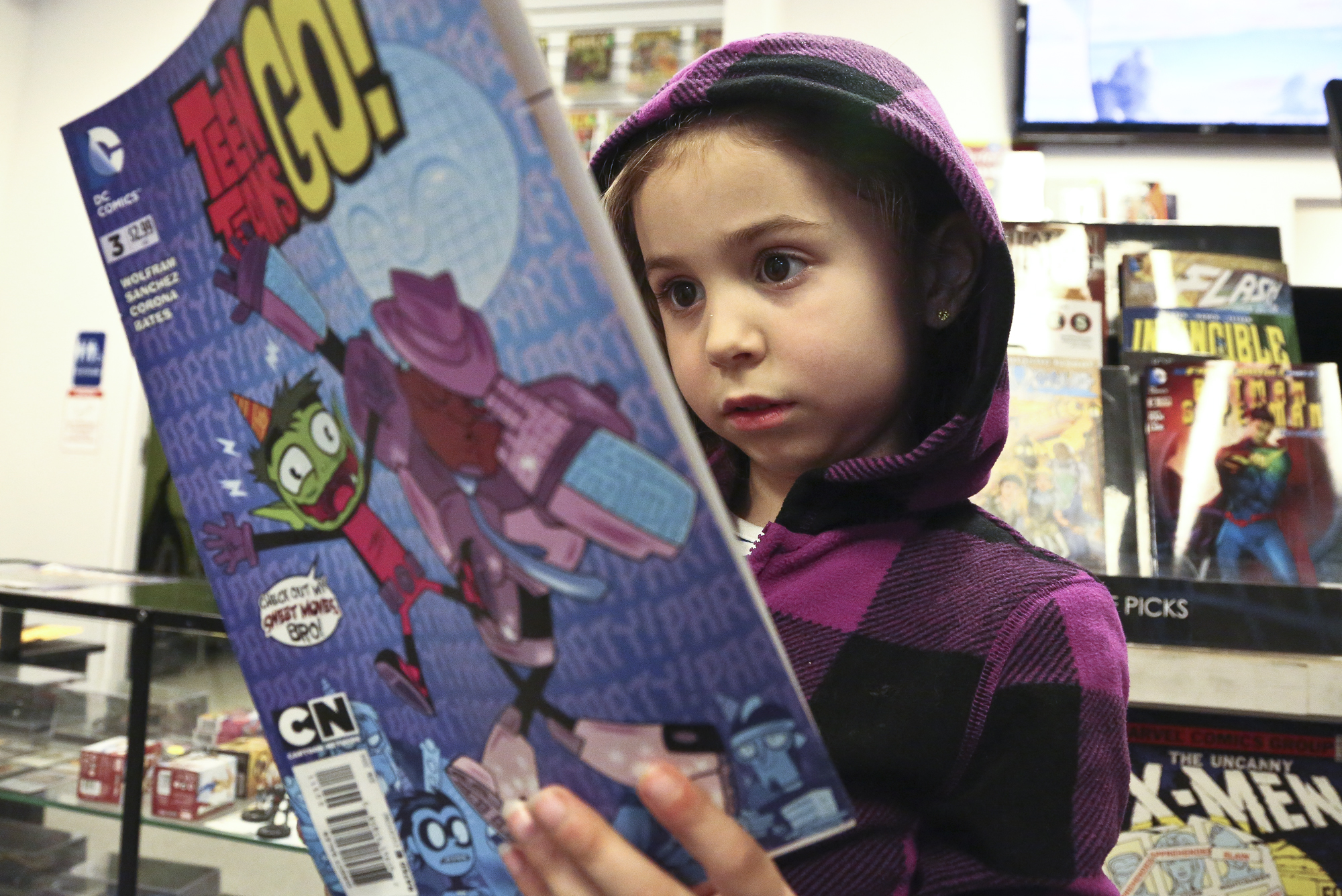 Kylie Hunt, 6 reads the comic book "Teen Titans Go!" as she waits for her father Bill Hunt of Felton to finalize his comic book purchases at Planet X Comics and Collectibles in York Township Friday, April 25, 2014. Kylie dressed up as a Bat Girl last year Bill said. Photo by Sonya Paclob