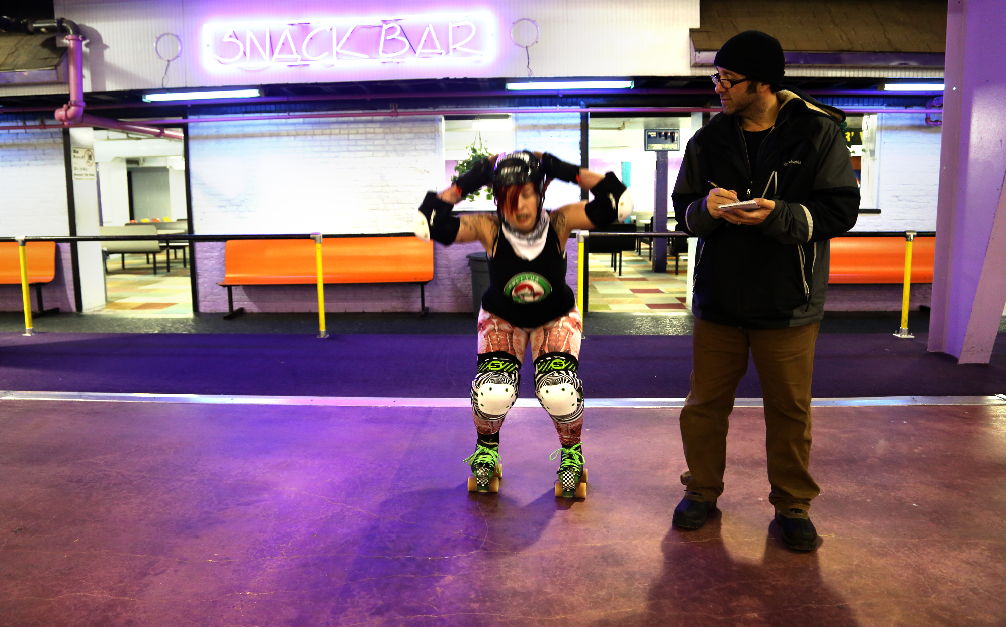 Jason Plotkin, York Daily Record photojournalist, takes notes do derby woman squatting in skates. 