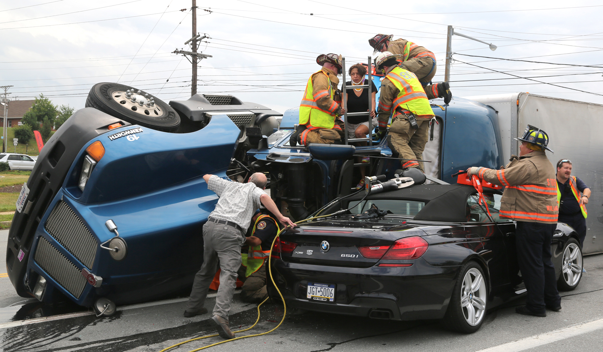 Ruth Mejia of La Feria, Texas, is being assisted by firefighters from York Area United Fire & Rescue and Wrightsville Rescue Company at the intersection of Haines Rd. and Mt. Rose Ave. in Springettsbury Township, Tuesday, July 15. 2014. Mejia was the passenger of Freddie Conde, the driver who's tractor-truck flipped on it's side. "My breaks went out coming down the road," Conde said, "I tried to go into the grass." Sonya Paclob - Daily Record / Sunday News