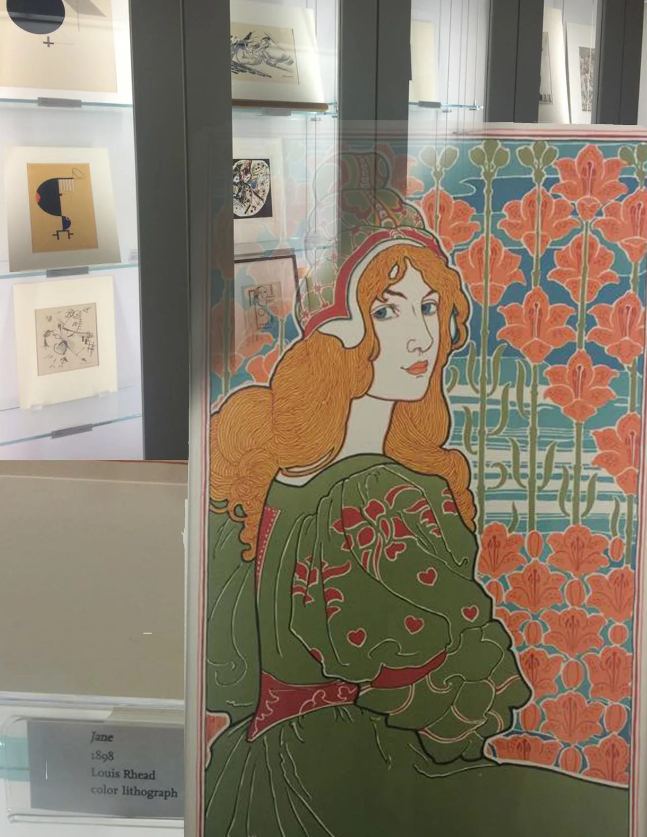 By John Webb
Recently I visited the UMMA and got the opportunity to view the study cases. I was excited to see a wide variety of pieces from the most abstract, to extremely commercial uses of Graphic Design. One of the pieces that stood out to me the most was Jane by Louis Rhead. It is a breathtakingly beautiful piece of art just because of how it was designed, but being printed as a lithograph gives it a final touch of perfection. I was very happy with the art on display in the study cases and will definitely come back again.