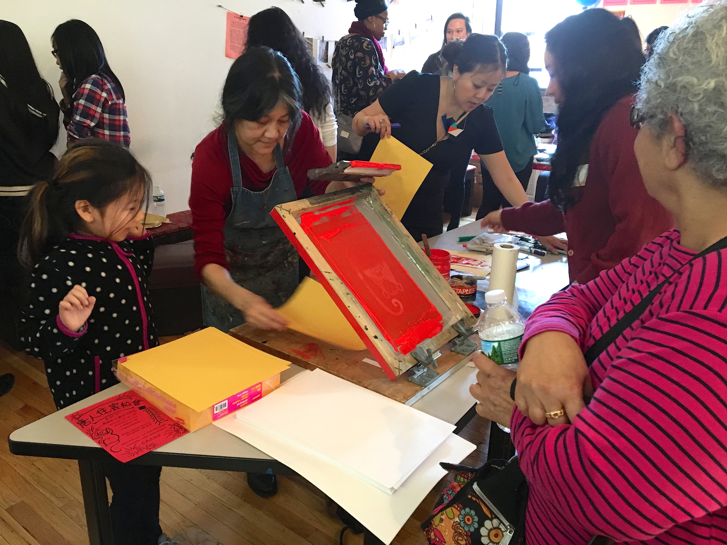 Chinatown Art Brigade's silkscreening station at CTU's Lunar New Year party. Tenants, youth, and volunteers took turns at the silkscreen station, designed and produced by Tomie Arai.