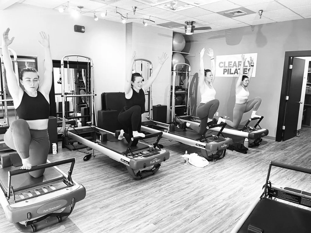 A small group of women using the reformer during a group equipment class.