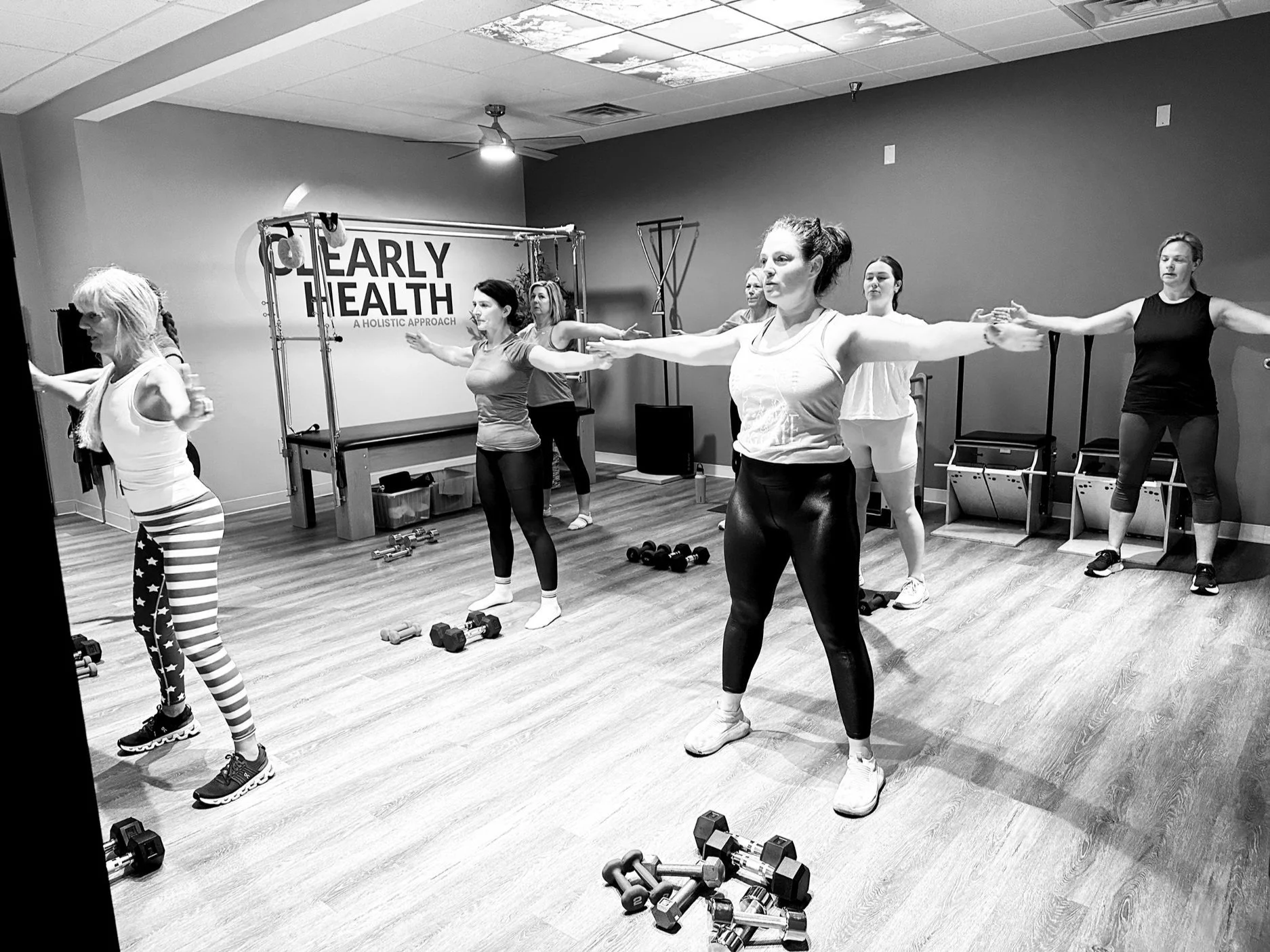 An instructor demonstrating exercise with weights to group during mat and strength class.