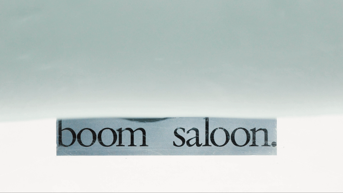 A sign with the words 'boom saloon' visible, seen from below, with the top part covered.