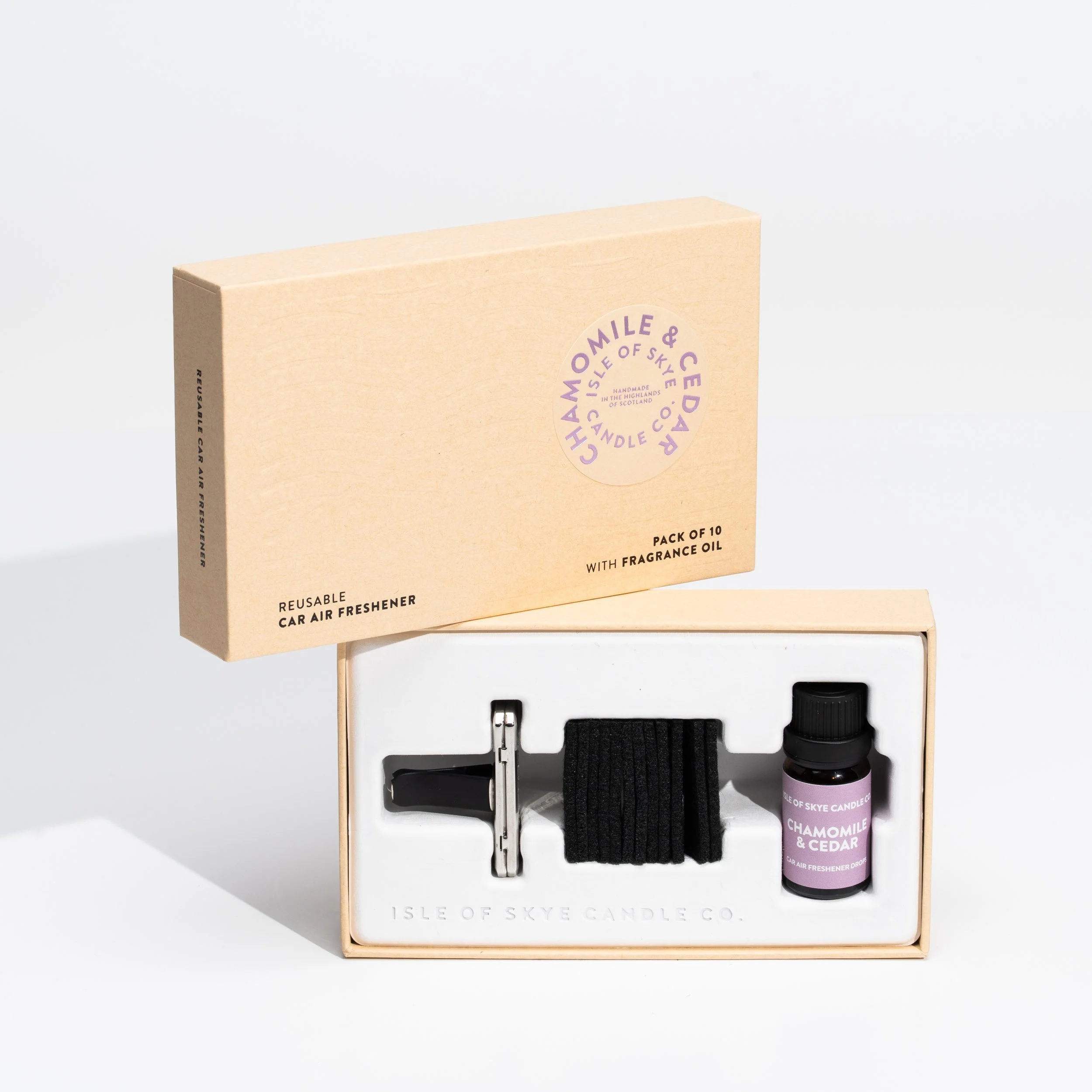 A boxed set of reusable car air fresheners with fragrance oil in a black bottle, a metal clip, and black straps, labeled 'Chamomile & Cedar' from Isle of Skye Candle Co.
