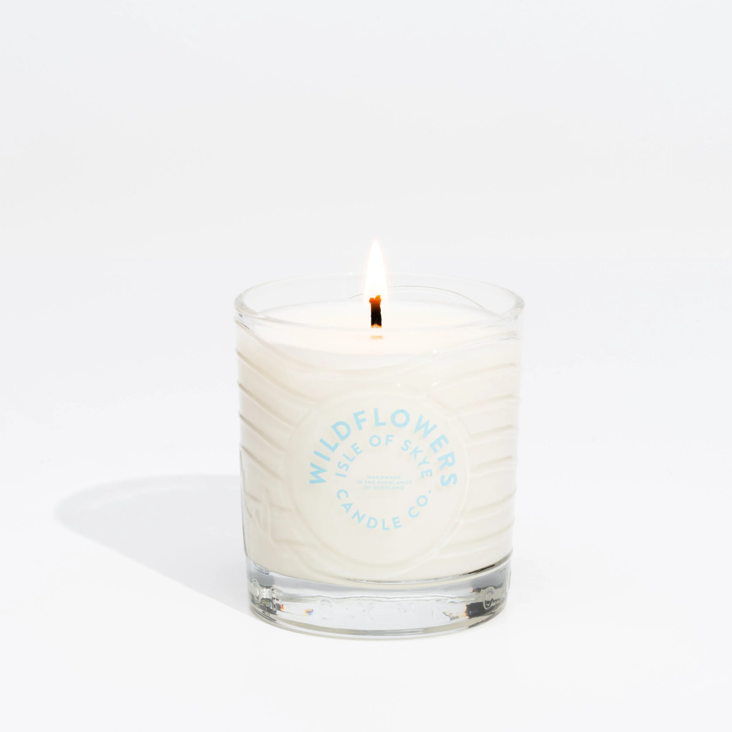 White scented candle in a glass holder with the label 'Wildflowers Isle of Skye Candle Co.'
