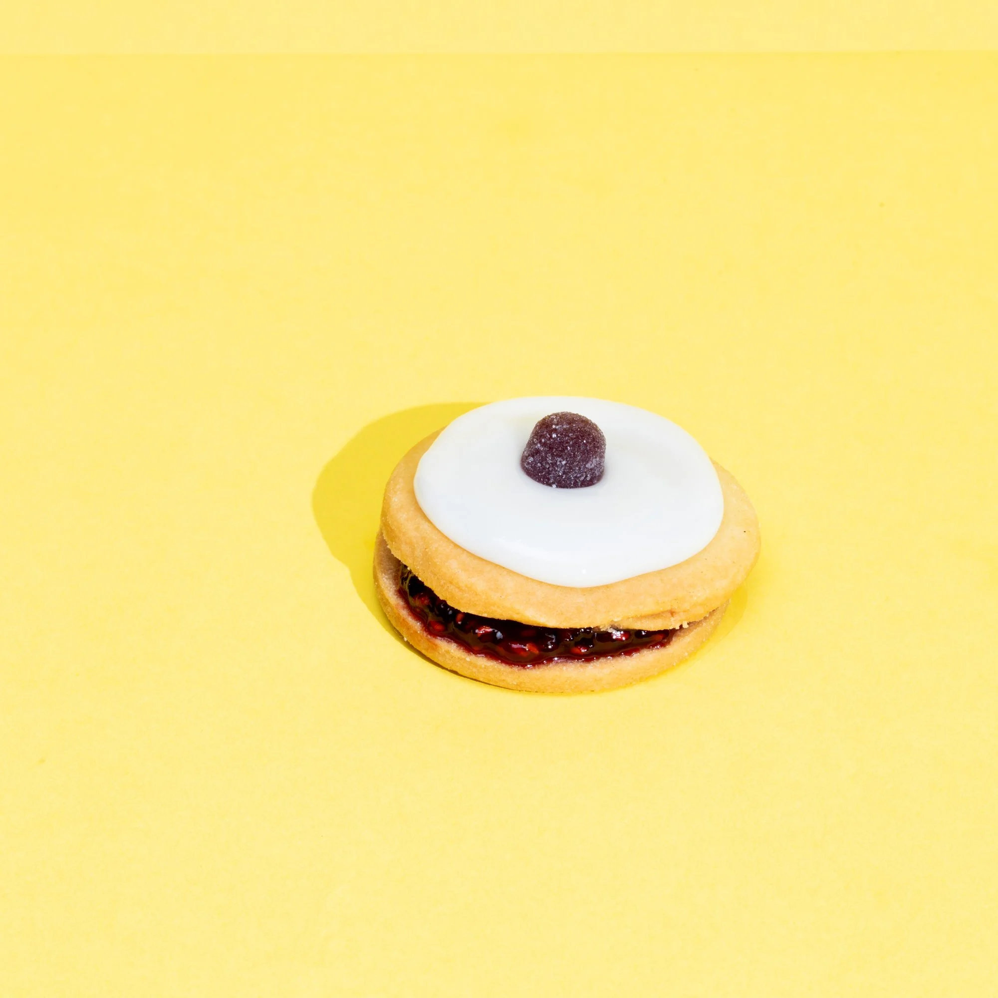 A JSON object with a string describing a cookie with white icing and a dark berry on top, on a yellow background.