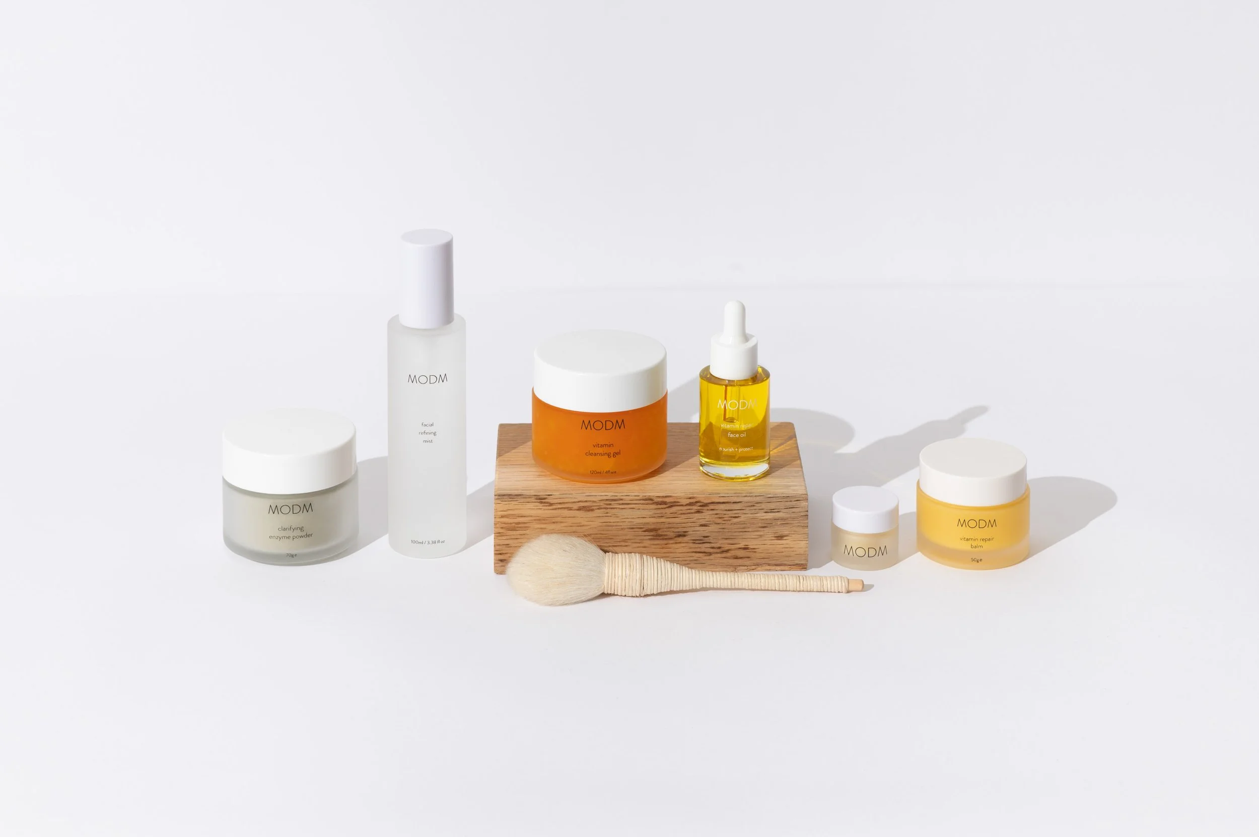 Collection of skincare products on a white surface, including cream jars, bottles, and a facial brush.