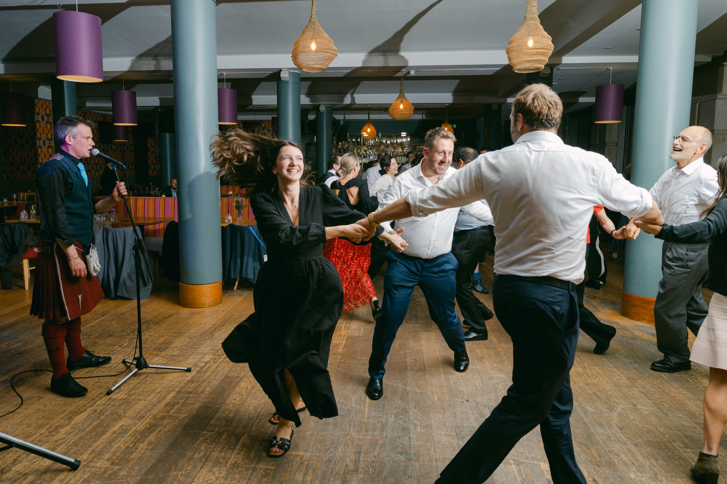 People dancing and having fun at a social event or party, with a musician playing a keyboard in the background.