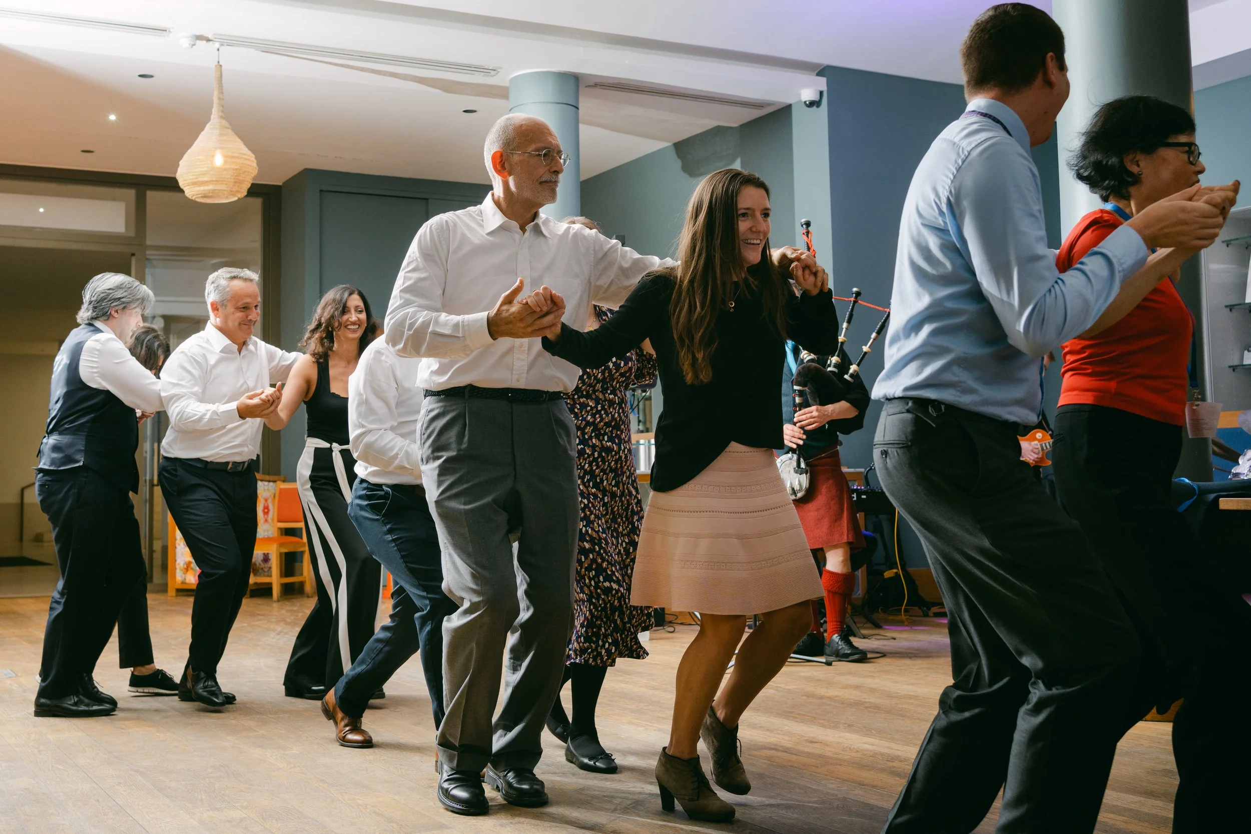 A group of people dancing in a line at an indoor event or party.