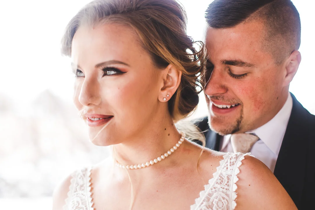 Closeup of bride and groom smiling with bright light behind