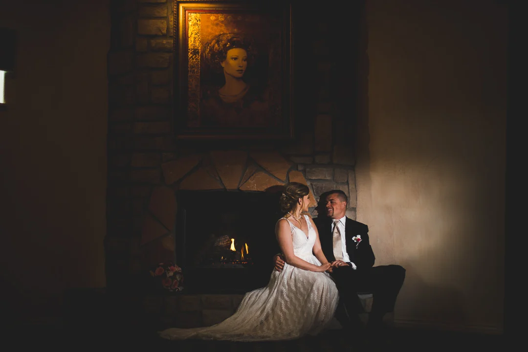 Couple sitting on hearth next to fireplace with painting above them