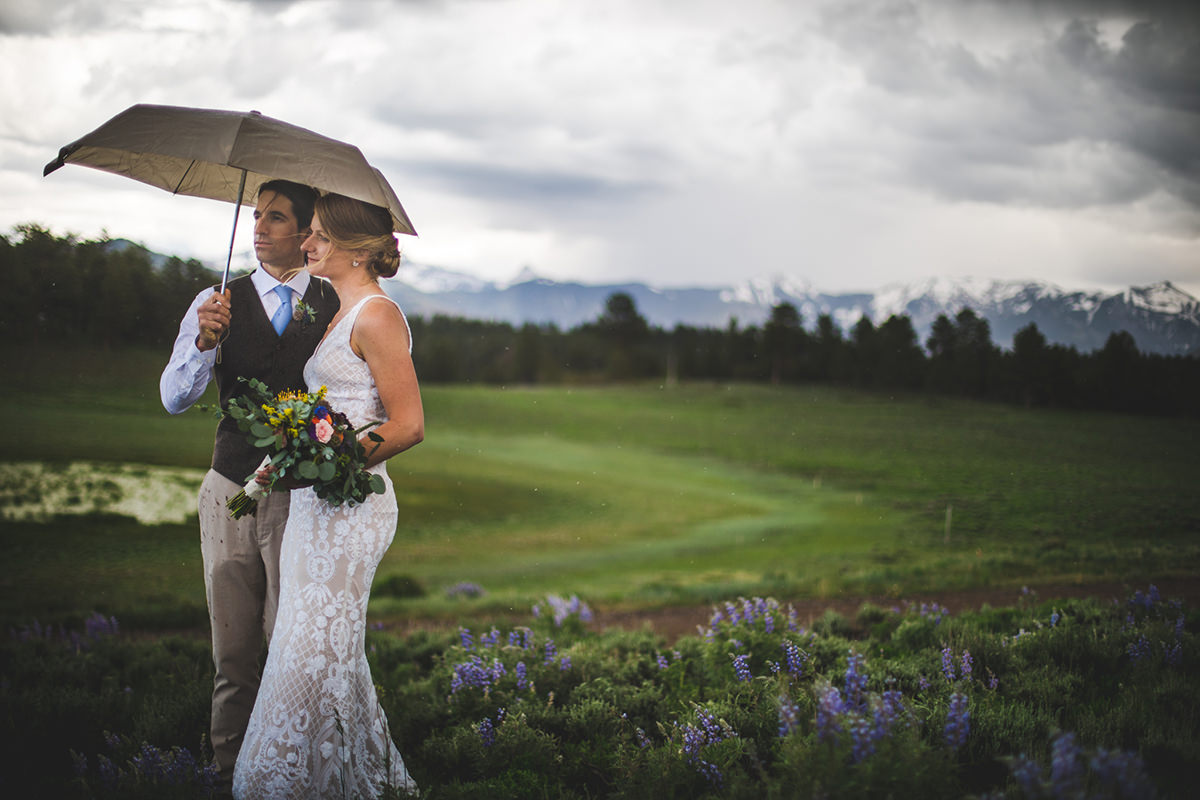 Groom and Bride under umbrella while rain sprinkles down