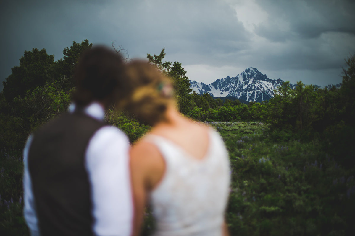Bride and groom holding each other looking at Mount Sneffels