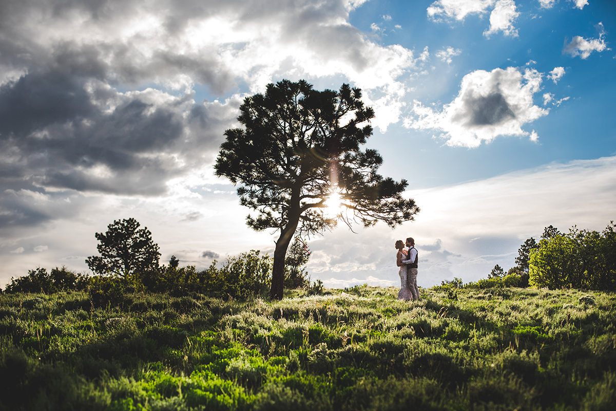 Silhouette of bride and groom with tree and sun behind them