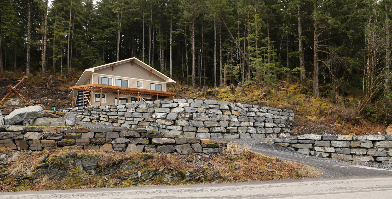 A new home built on a terrace with a stackwall, or stone retaining wall. The contractor compensated for the slope of the terrain and curved the wall around a corner.