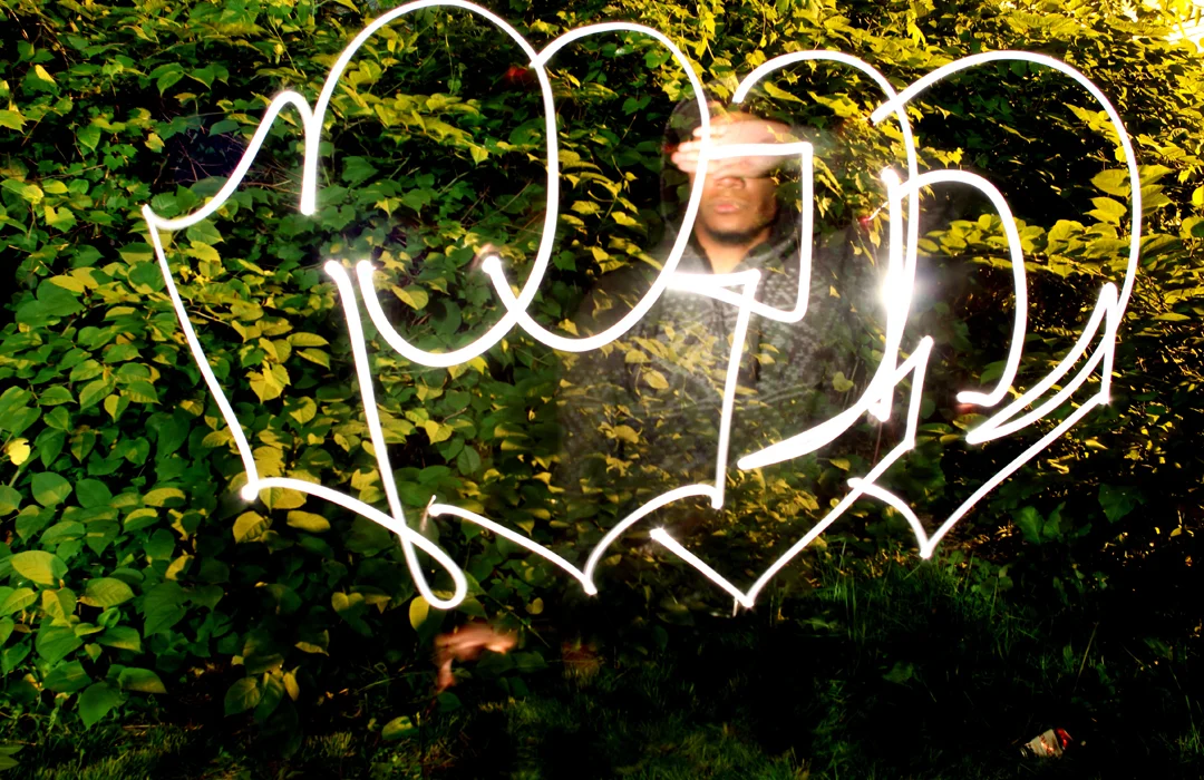 Graffiti artist RILA poses for a portrait after writing his name with a flashlight in Chicago IL.