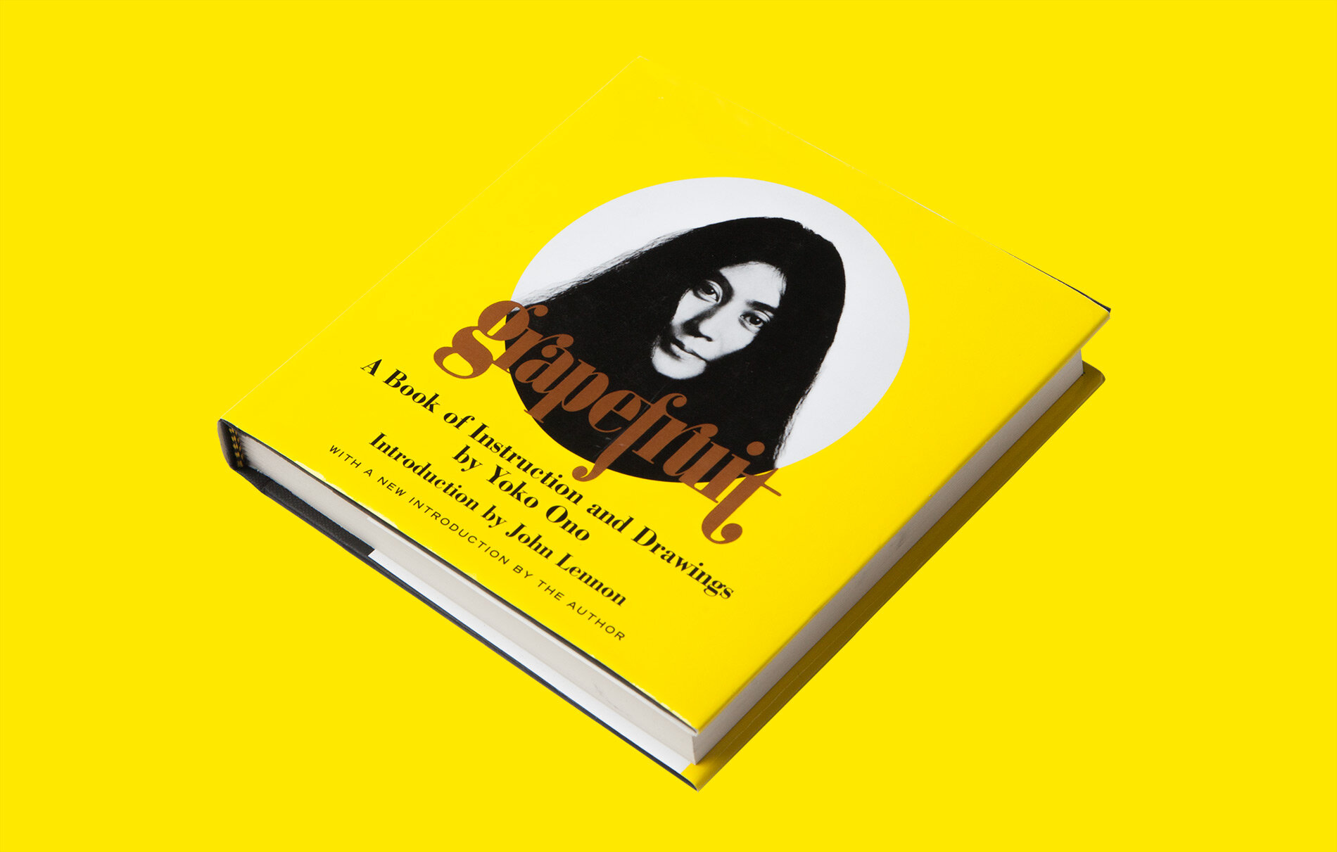 A bright yellow book titled "Grapefruit" with a black and white photo of a woman on the cover. The book includes instruction and drawing tips by Yoko Ono, with a new introduction by John Lennon.