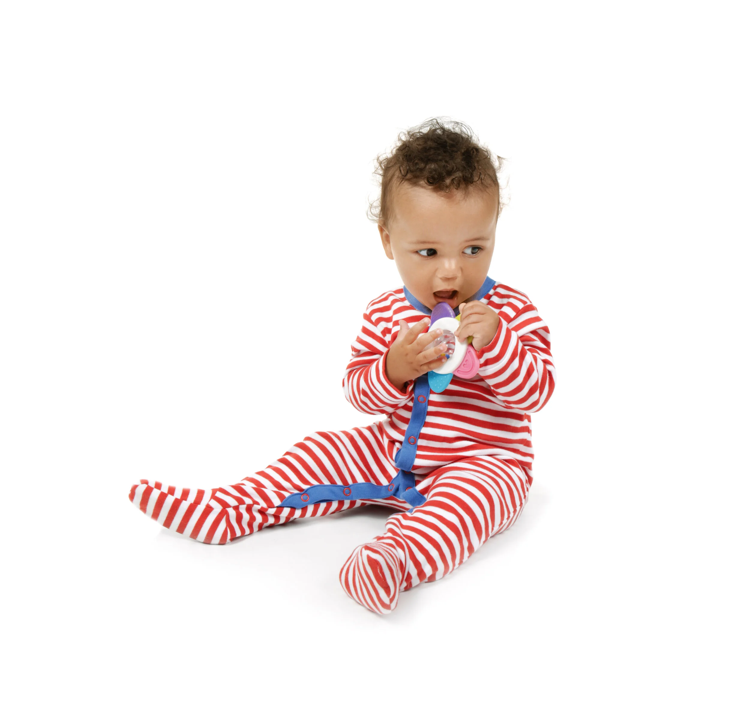 A young child sitting on the floor wearing a red and white striped pajama set, holding a toy and looking to the side with an inquisitive expression.
