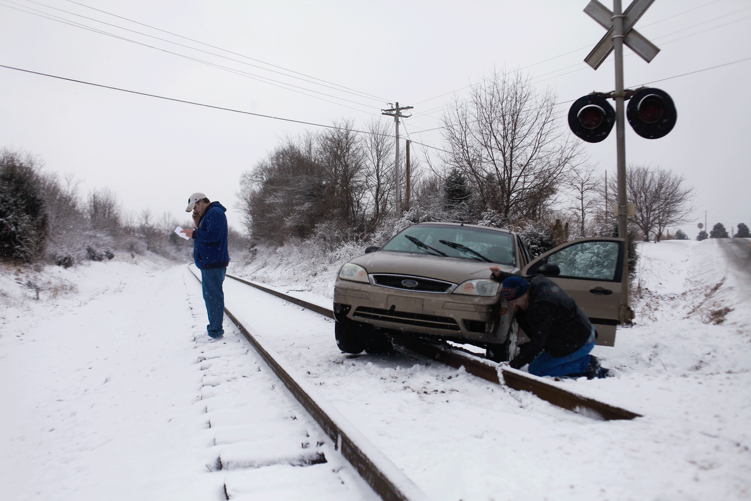 Thomas Hansman makes a call while Steve Nolan attaches a chain to Hansman's car on the train tracks crossing Highway 146. Nolan stopped when he saw Hansman on the tracks. When asked why he stopped to help Nolan replied, "A train could have come along at any time. It's just what you do."