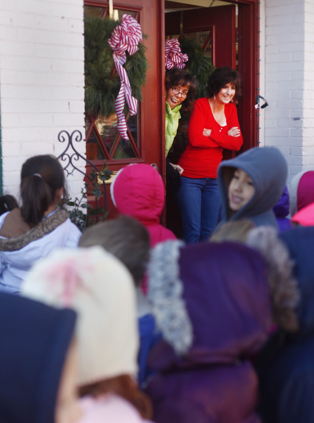 Karen Eldridge and Bobbi Kelly peek out of Karen's Book Barn in downtown La Grange to see kindergardeners from La Grange Elementary singing Christmas carols.