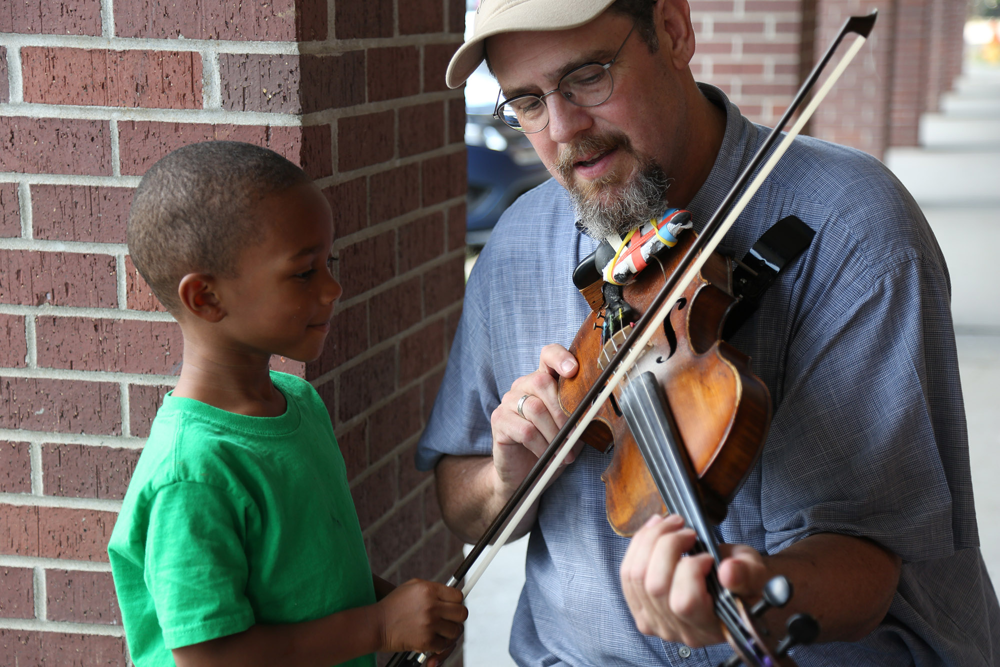  Tom Cunningham explains how he plays the violin at an event that celebrated military families. 