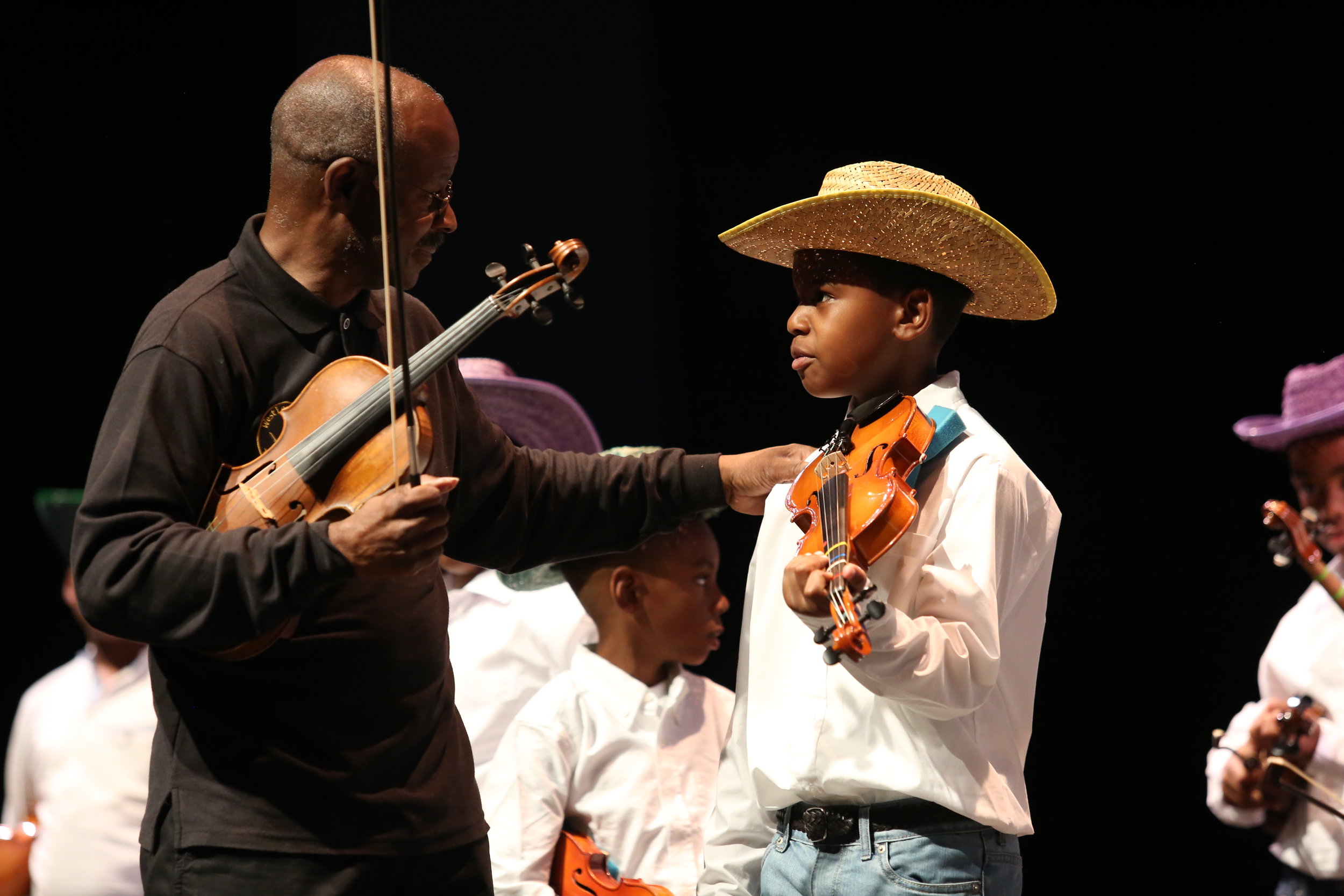  Mr. Keith Cook, ArtsReach violin instructor, helps a Young Masters violin student get ready to perform at The ArtsReach Showcase.  For more photos from that night: https://www.flickr.com/photos/kentuckycenter/albums/72157684538345165  