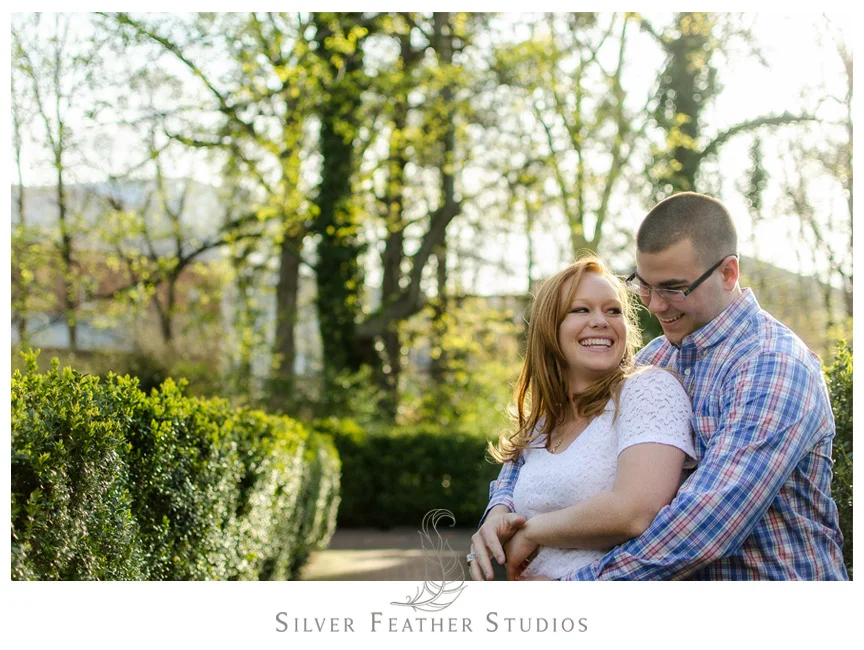 Hugs in the bushes at this UNC engagement session in Chapel Hill. © Silver Feather Studios, Chapel Hill Wedding Photography and Videography